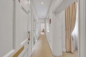Ein Flur mit weißen Wänden, beigeem Teppich und einem Vorhang in Beige auf der rechten Seite.