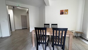 Ein Essbereich mit einem Holztisch und Stühlen, einem kleinen runden Tisch sowie zwei an der Wand befestigten religiösen Bildern.