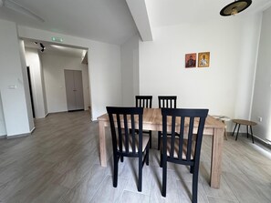En matplats med ett bord och stolar i trä, ett litet runt bord och två religiösa ikoner som hänger på väggen.