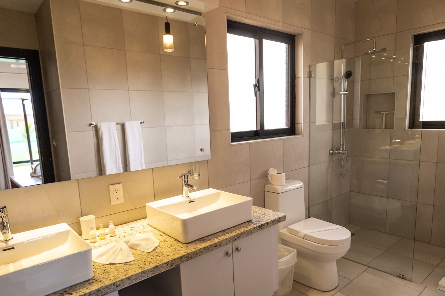 A modern bathroom with two sinks, a toilet, and a shower.