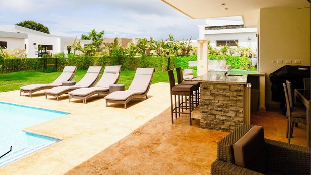 Un espace aménagé au bord de la piscine, avec des chaises longues et un bar.