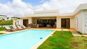 Une maison moderne dotée d’une piscine, d’un espace salon extérieur et d’un patio.