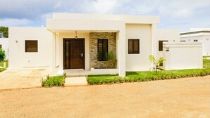 Une maison moderne à deux étages, dotée d’une façade en pierre, d’une porte d’entrée et d’un petit jardin.