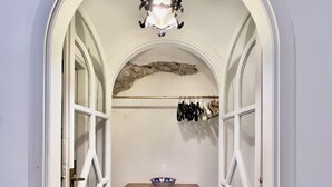 Un couloir voûté avec une commode en bois, un porte-chaussures suspendu et un luminaire décoratif au plafond.
