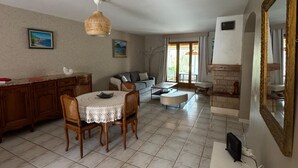 Un amplio salón con una mesa de comedor, sillas, un sofá y una chimenea.