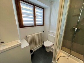 A small bathroom with a toilet, a radiator, a shower, and a window with blinds. - Detached 5-bedroom family chalet in La Rosière-Centre. (Montvalezan)