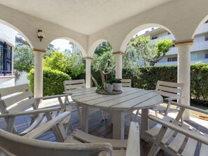An outdoor patio with a round table and white benches, surrounded by arches and greenery. - Cervantes by Interhome (Cambrils)