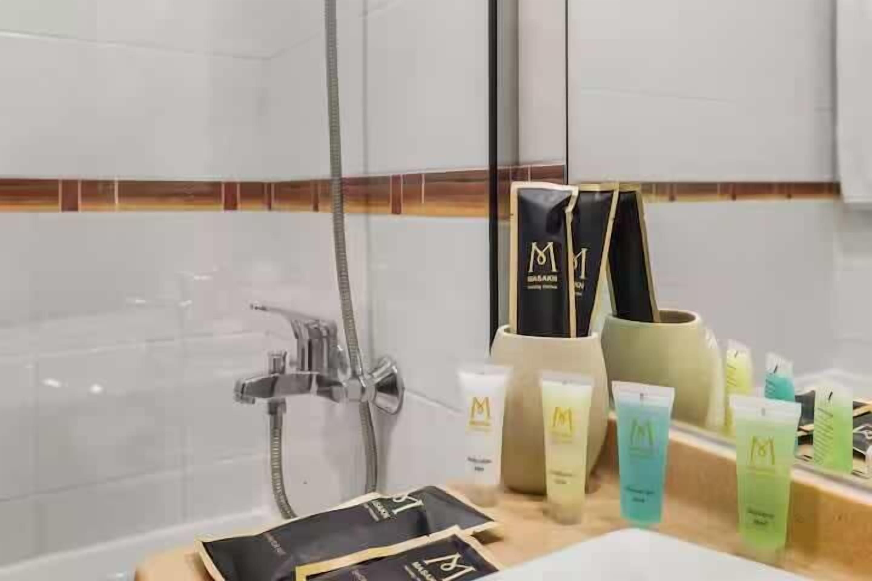 A bathroom with a shower, a vanity with toiletries, and a towel rack.