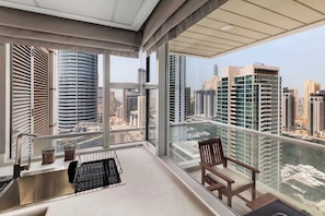 A balcony with a city view, a sink, and a chair. - Modern 2BR Marina Apt | Canal View | Pool & Sauna (Dubai)