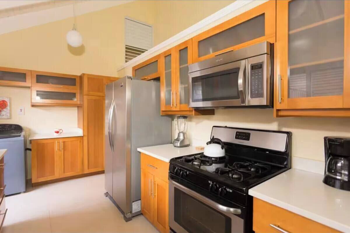 A kitchen with wooden cabinets, a stainless steel refrigerator, a microwave, a stove, and a coffee maker.