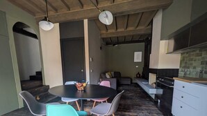 Une cuisine moderne dotée d’un îlot central, un coin repas avec une table ronde et des chaises, et un espace salon confortable avec un canapé et des coussins.