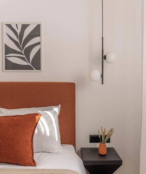 A bedroom with a bed, pillows, a nightstand, a wall-mounted lamp, and a framed artwork. - Sunlit Balcony | Family APT | Whirpool & Netflix (Kallithea)