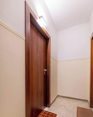 A hallway with a wooden door, a carpeted floor, and a light fixture above the door. - Sunlit Balcony | Family APT | Whirpool & Netflix (Kallithea)