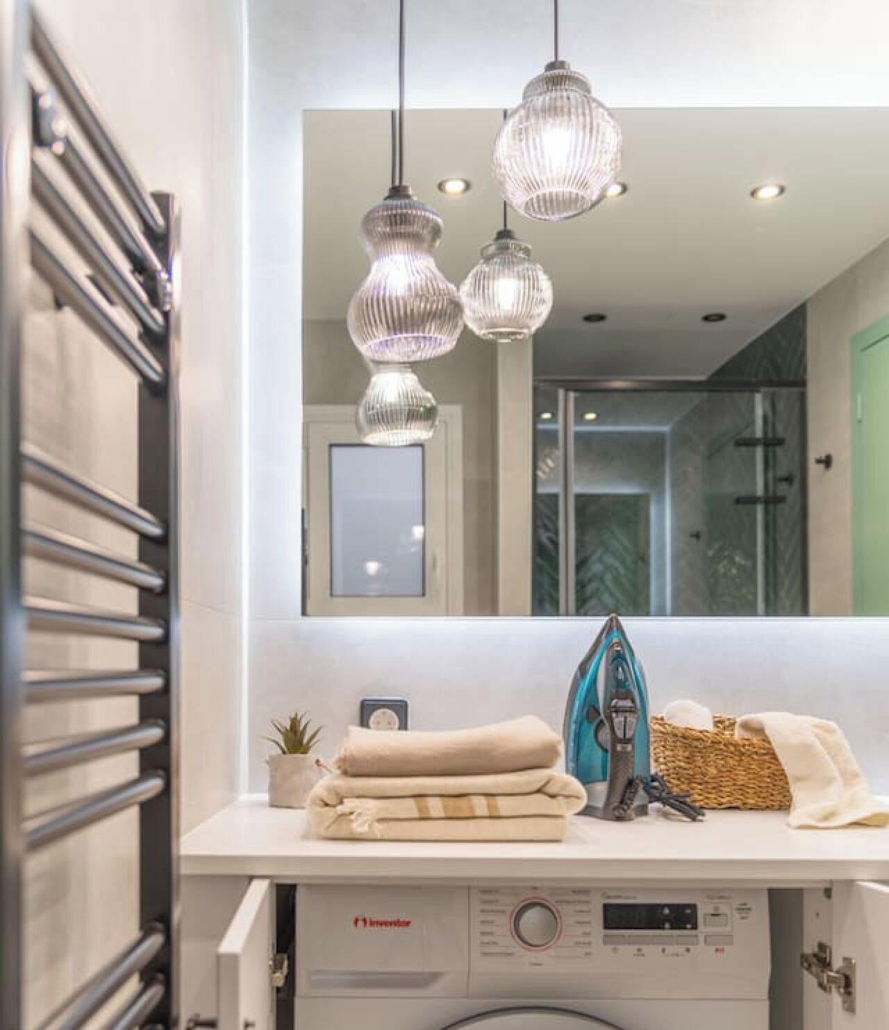 A modern bathroom with a large mirror, a towel rack, and a washing machine.