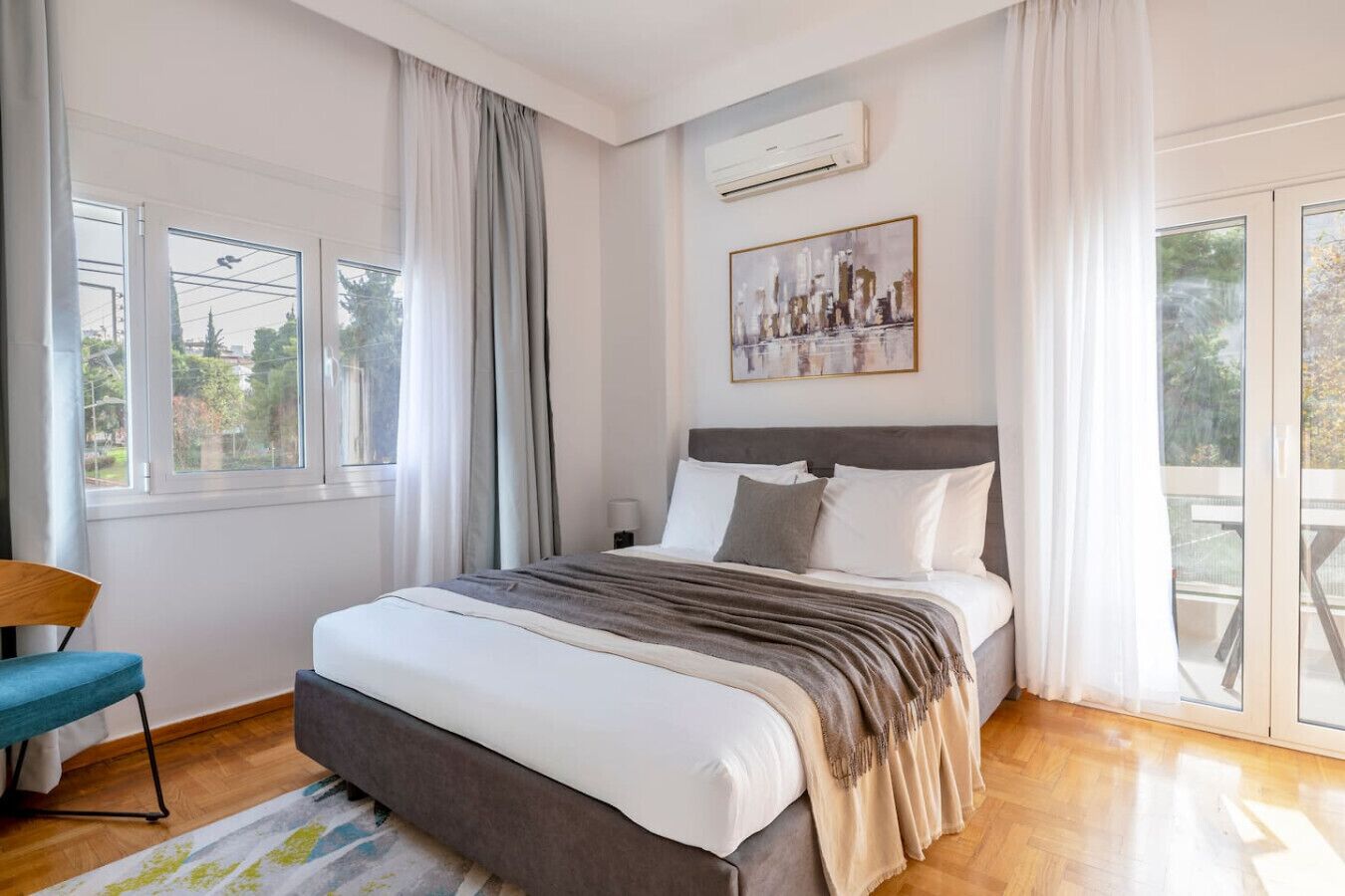 A bedroom with a bed, a chair, a window, and an air conditioning unit.