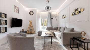 A modern living room with a sofa, armchair, TV, and decorative items.