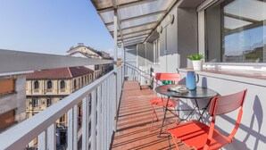 A balcony with a table and chairs, a potted plant, and a view of buildings in the background. - Bright and Modern Apartment by Wonderful Italy (Turin)