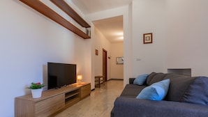 A modern living room with a flat-screen TV, wooden entertainment unit, and a grey sofa with blue cushions. - Bright and Modern Apartment by Wonderful Italy (Turin)