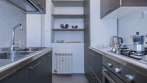 A modern kitchen with a stainless steel sink, a built-in oven, and a coffee maker. - Bright and Modern Apartment by Wonderful Italy (Turin)