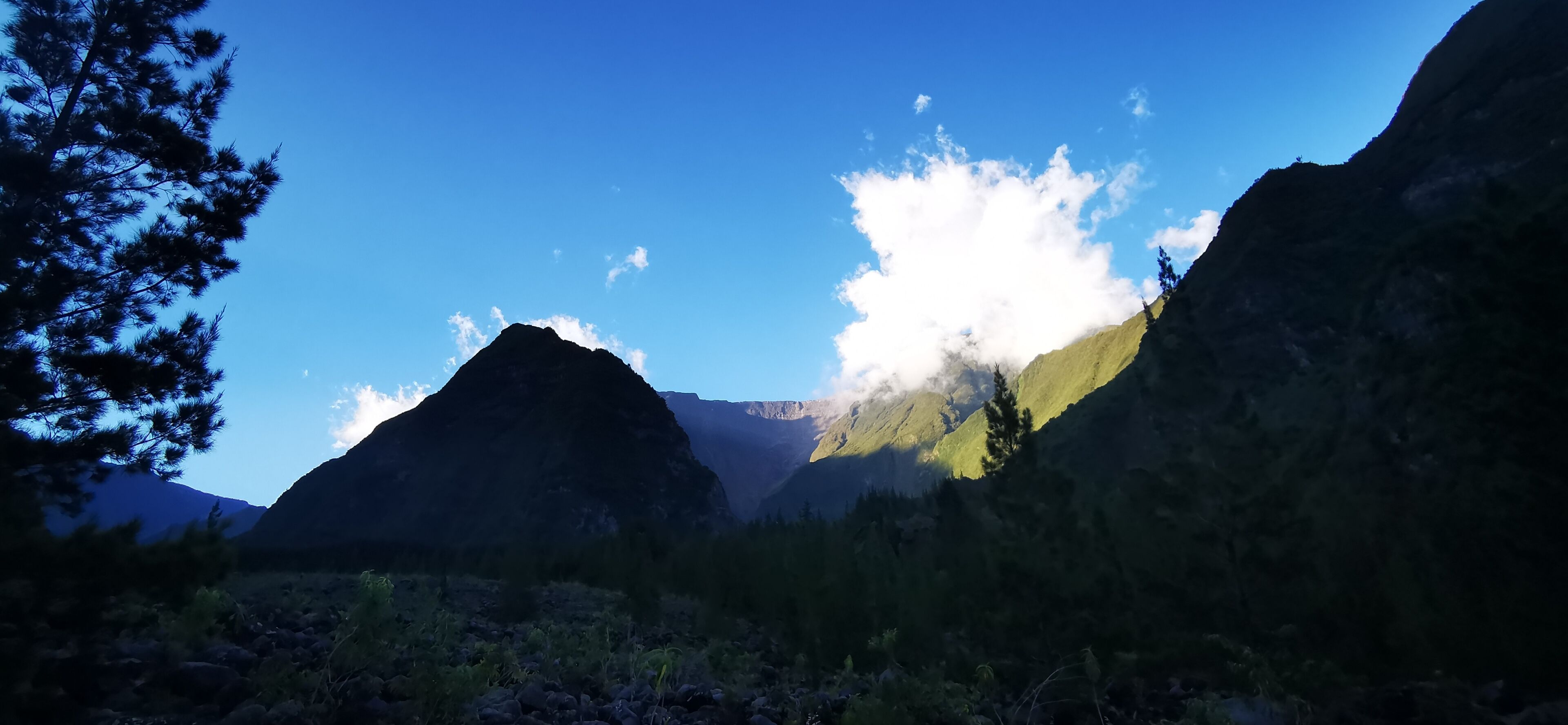 A mountainous landscape with a prominent peak and a clear blue sky.