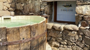 Un muro in pietra con una botte di legno e un cartello che riporta la scritta 'Ecolaguar Orarqueiro'.