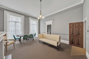 A dining area with a table and chairs, a sofa, and a chandelier. - Designer Mayfair Apartment (London)