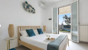 Un dormitorio con cama, una bandeja de comida y bebidas, decoración en la pared, y una vista a través de una puerta abierta.