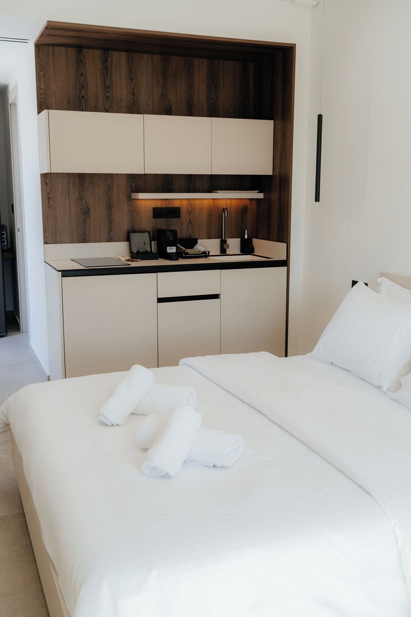 A hotel room with a bed, a desk with a computer, a coffee maker, and a sink.