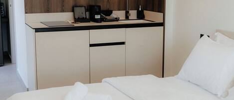 A hotel room with a bed, a desk with a computer, a coffee maker, and a sink.