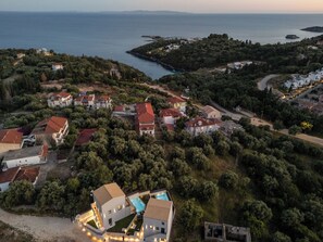 An aerial view of a coastal residential area with houses, a swimming pool, and a clear view of the sea. - Malou & Charma Villas (Igoumenitsa)