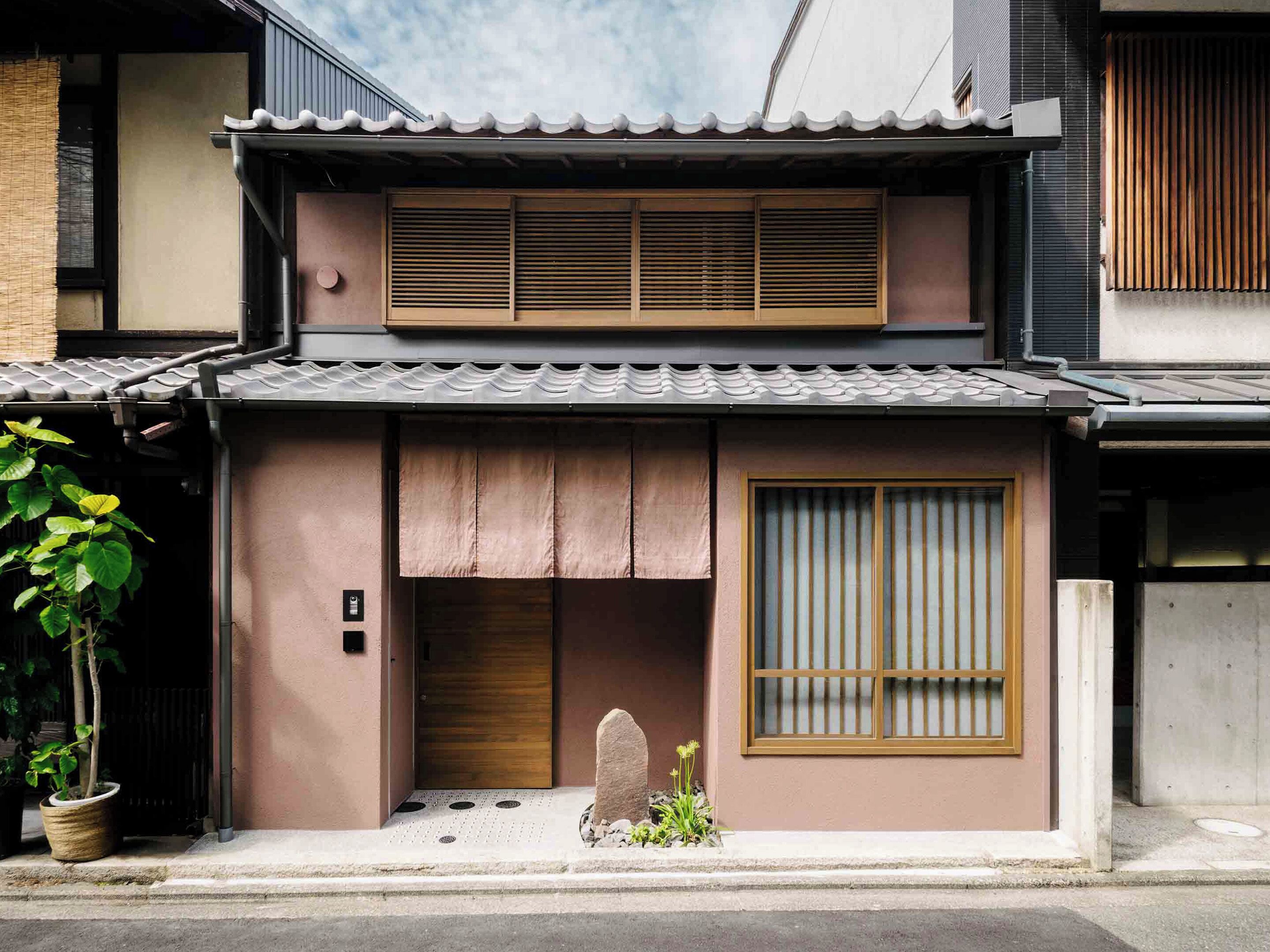 A traditional Japanese house with a tiled roof, sliding doors, and a small garden area with plants.