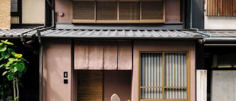 A traditional Japanese house with a tiled roof, sliding doors, and a small garden area with plants.