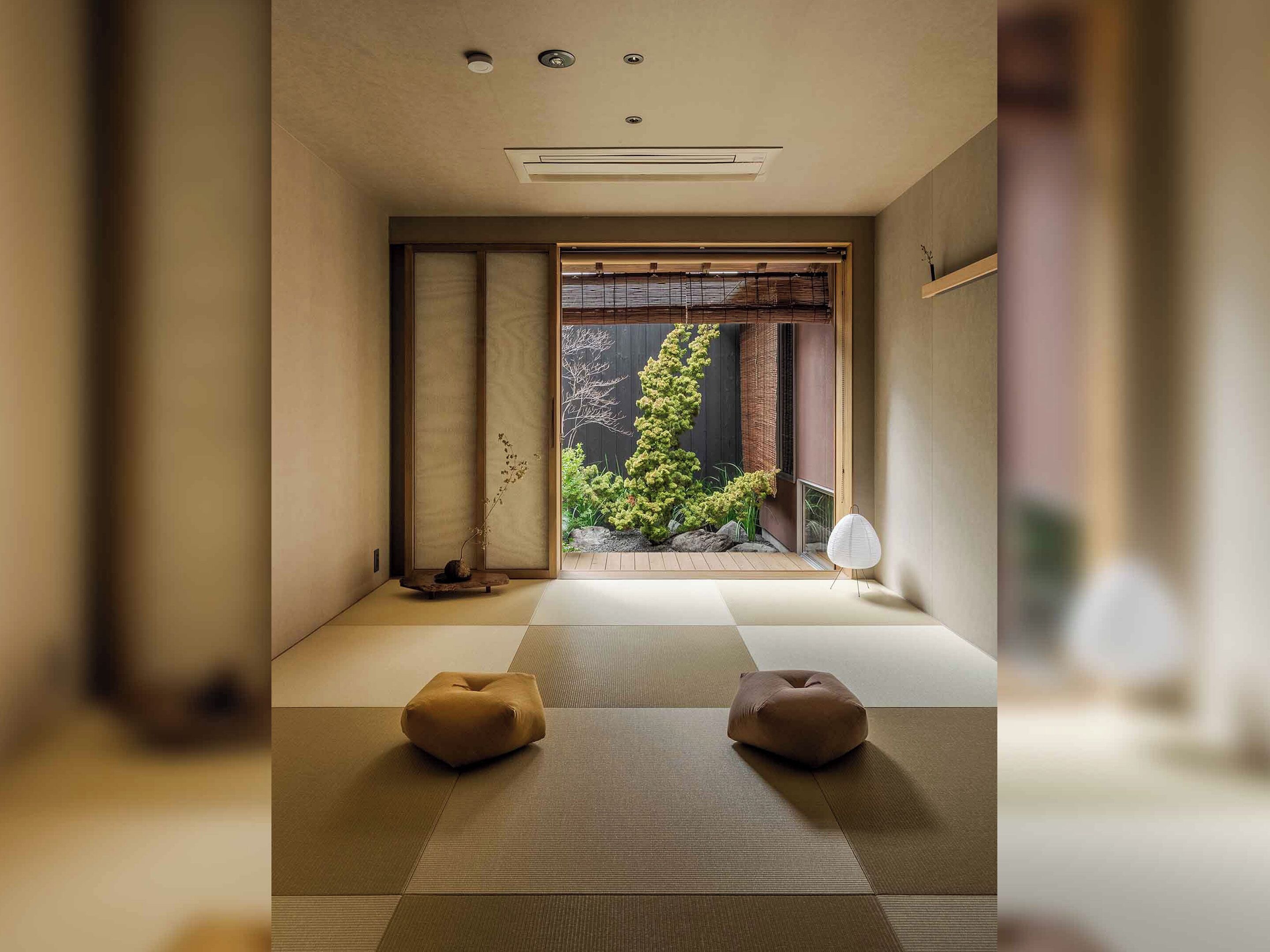 A traditional Japanese room with tatami flooring, a shoji screen, and a bonsai tree.