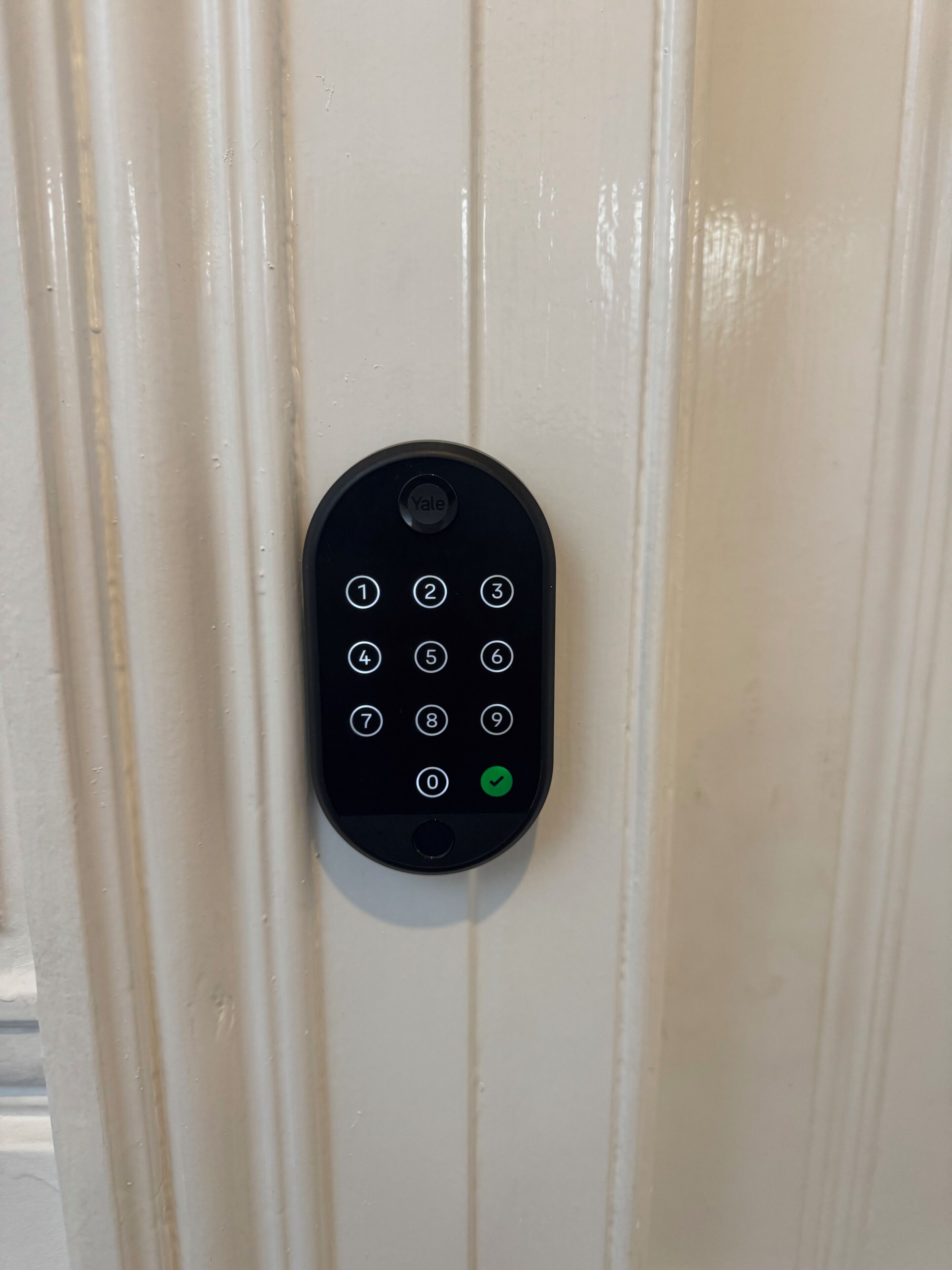Una cerradura inteligente Yale en una puerta blanca.