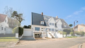 Une maison moderne à deux étages, avec un toit gris, un petit balcon et une entrée à l’avant.