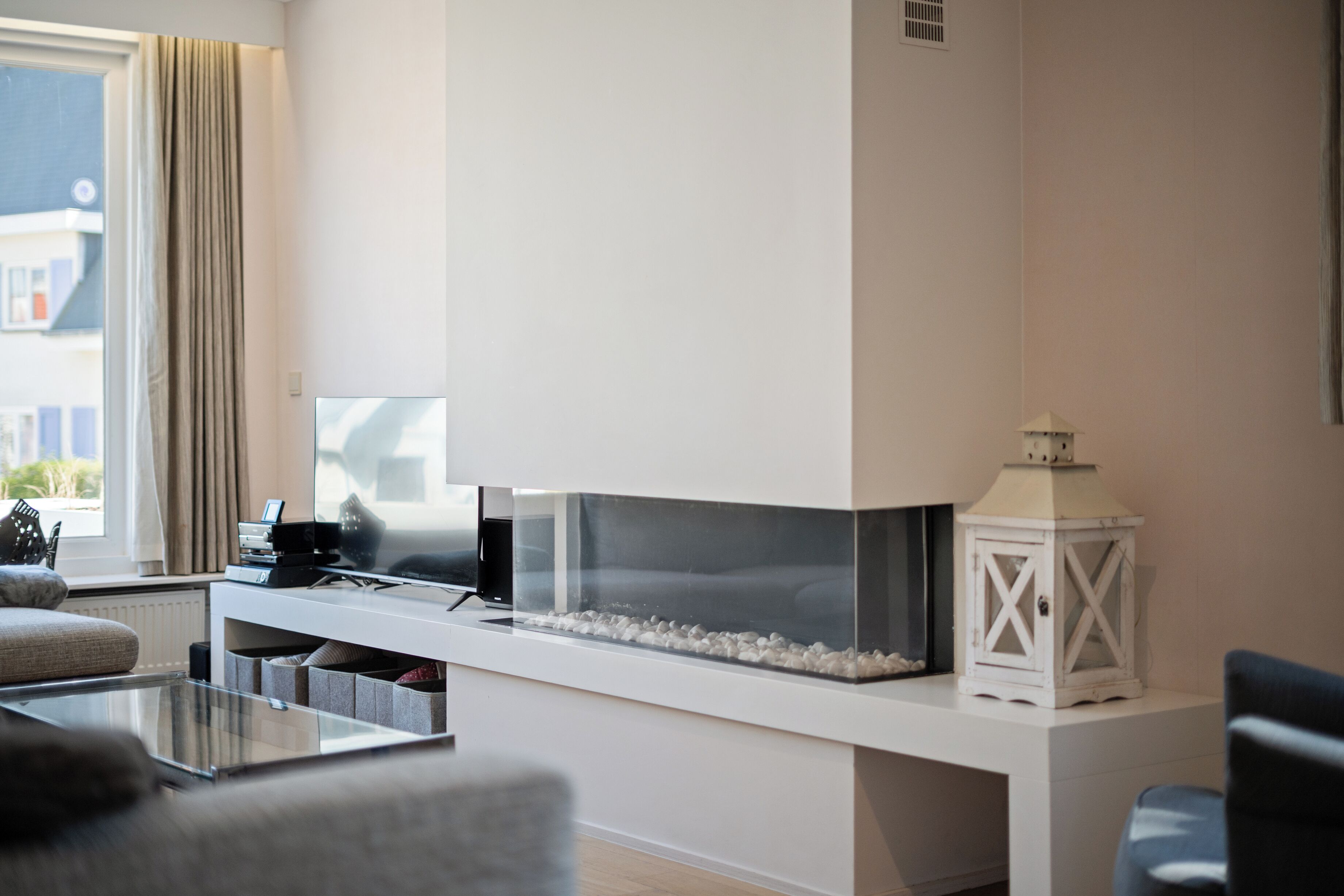 A modern living room with a large flat-screen TV, a fireplace, and a white console table.
