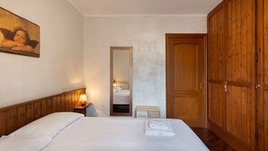 Hotellihuone, jossa on suuri sänky, puinen vaatekaappi, peili ja taulu seinällä.