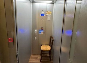 An elevator with a chair in the center, a control panel on the left, and a sign on the wall. - Ferme de la viguerie: country house between Quézac and Maurs (Maurs)