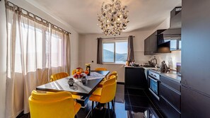 A modern kitchen with a dining area, featuring a chandelier, yellow chairs, and a view of the outdoors. - Villa Franka by Villas Guide (Vela Luka)