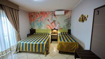 Habitación de hotel con dos camas, aire acondicionado de pared, mesita de noche y un banco.