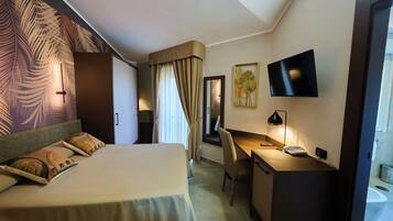 Ein Hotelzimmer mit Bett, Schreibtisch, Stuhl, Fernseher und einem durchgegangenen Tür sichtbaren Badezimmer.