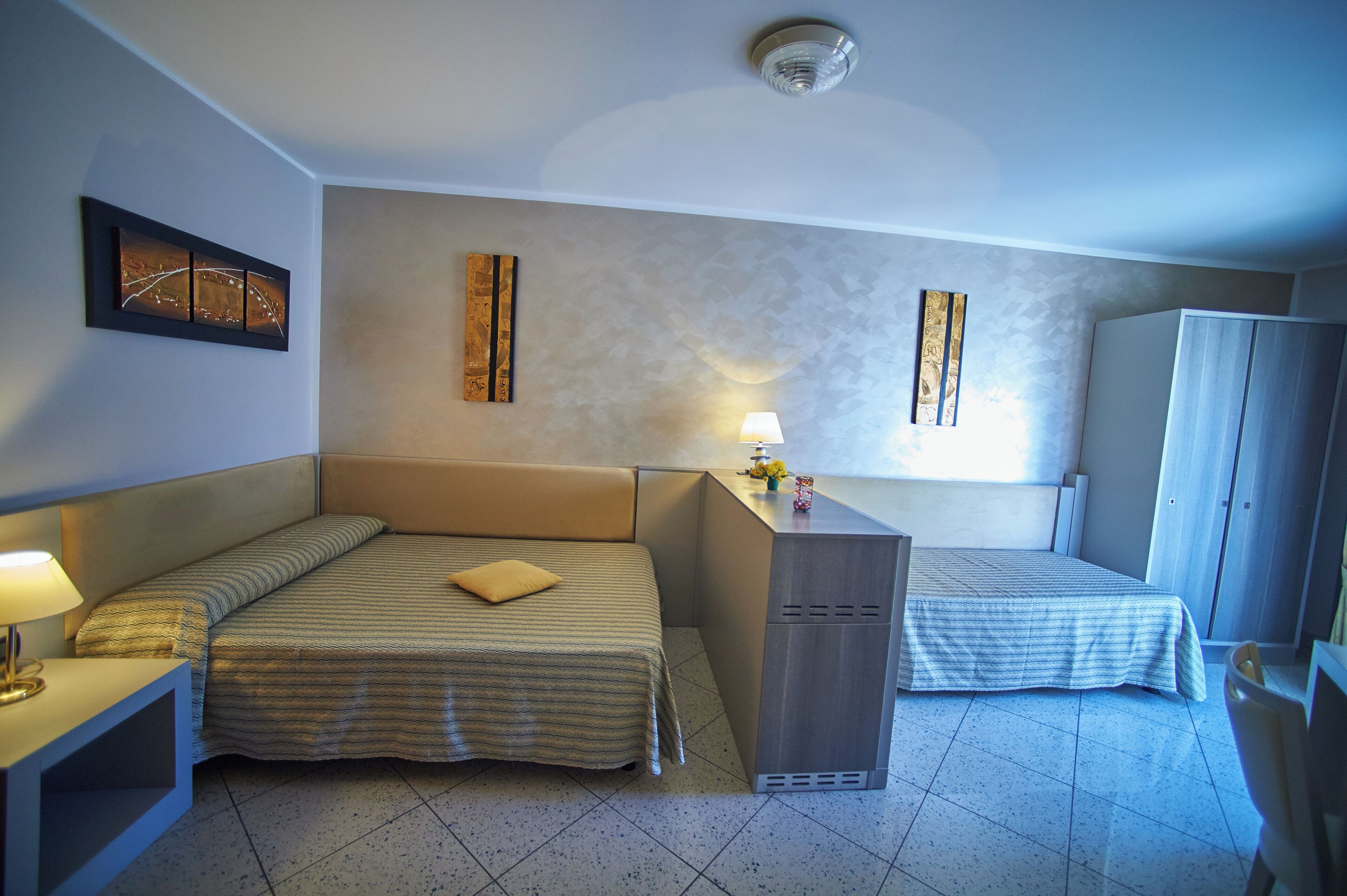 Una camera d'albergo con due letti, una scrivania e un armadio.