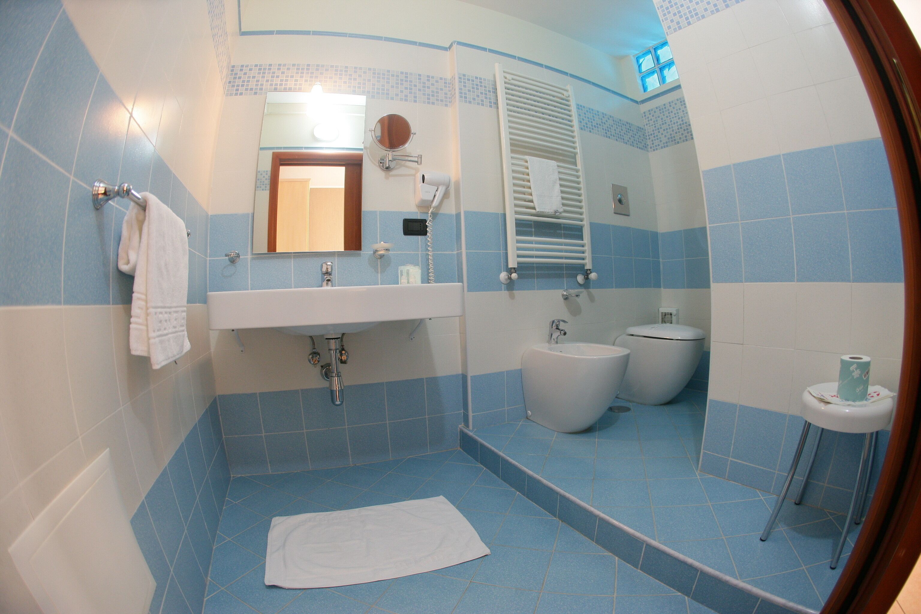 A bathroom with a sink, mirror, towel rack, toilet, and bidet.