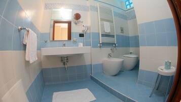 A bathroom with a sink, mirror, towel rack, toilet, and bidet.