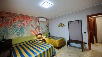 A hotel room with two beds, a desk, a chair, a bench, a wall-mounted air conditioner, and a door.