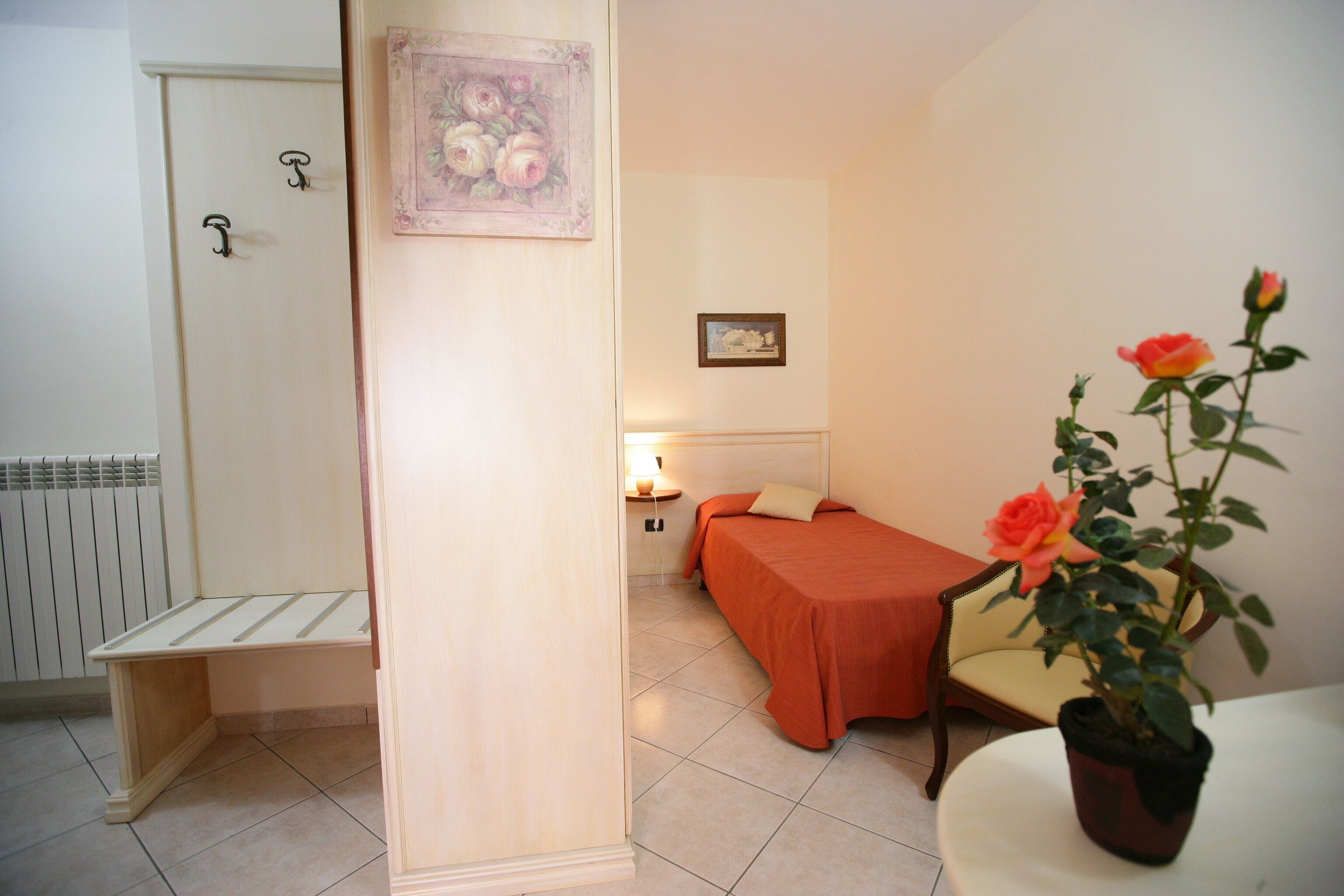 Une chambre à coucher avec un lit, une chaise, une plante en pot et un radiateur.
