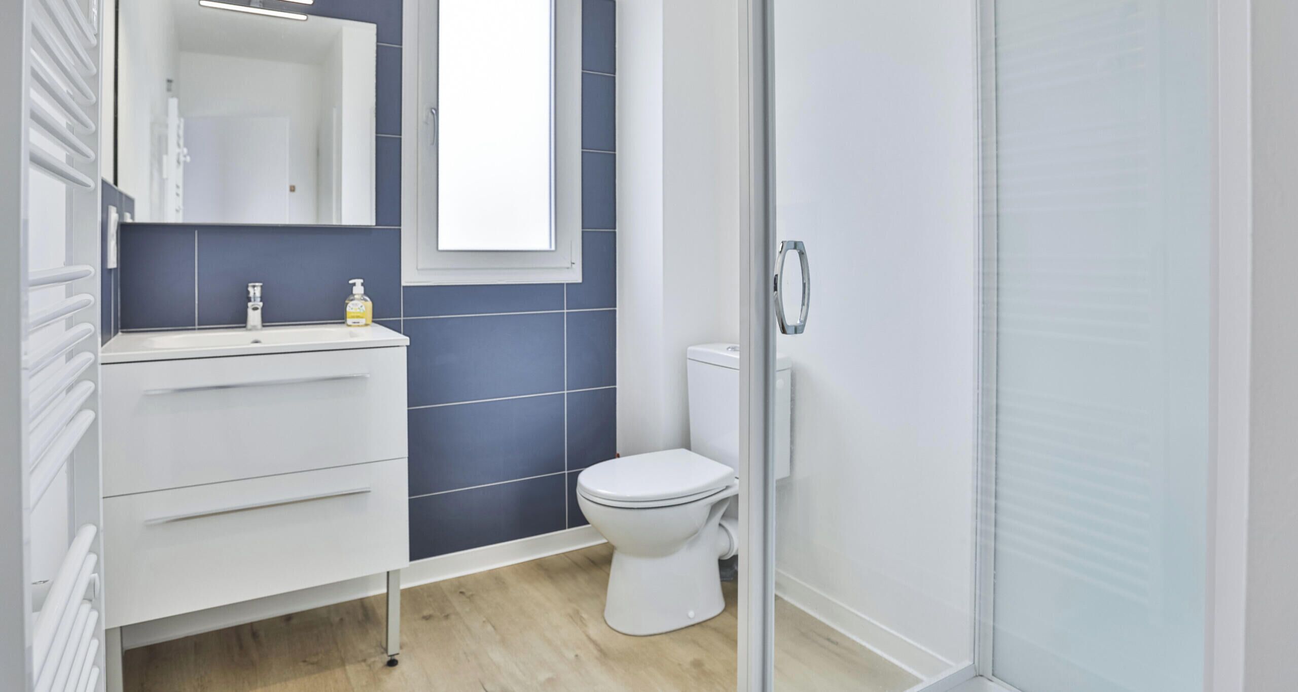 A modern bathroom with a white sink, mirror, and toilet.