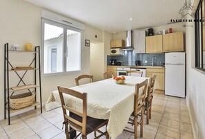 A compact kitchen with a dining area, featuring a table with chairs, a microwave, a stove, and a refrigerator. - Ker Victor I Jolie maison de ville 6 voyageurs (Les Sables-d´Olonne)