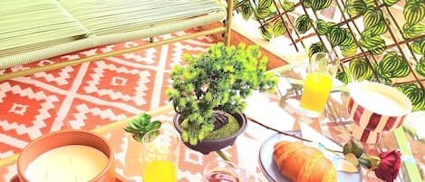 A table set with a candle, a glass of orange juice, a glass of tea, a croissant, and a rose.