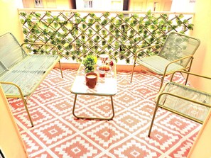 A balcony with a patterned floor, two metal chairs, a small table with a plant and a glass of drink, and a lattice with green leaves. - Tranquil 2-bedroom apartment with AC in charming Nice (Nice)